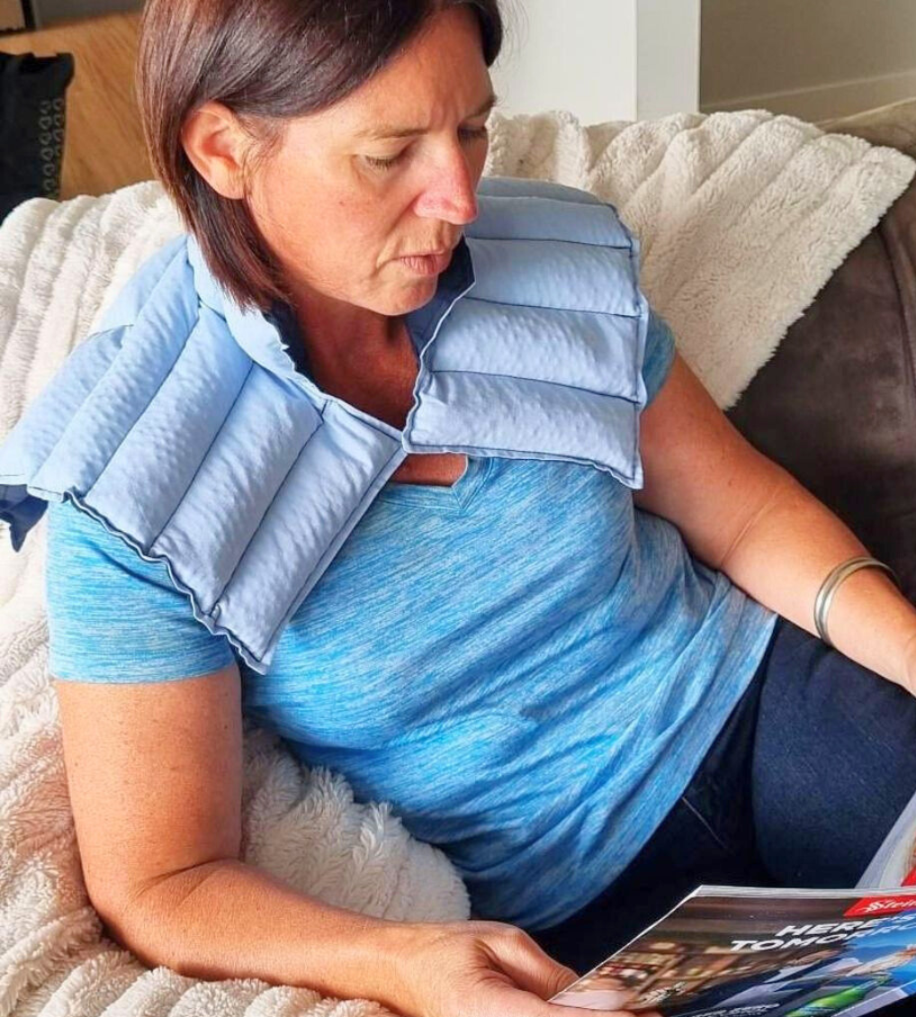 Lady_sitting_on_couch_wearing_a_blue_neck_shoulder_wheat_bag