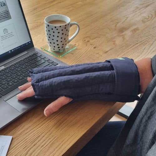 Lady wearing the glove wheat bag while working on her laptop