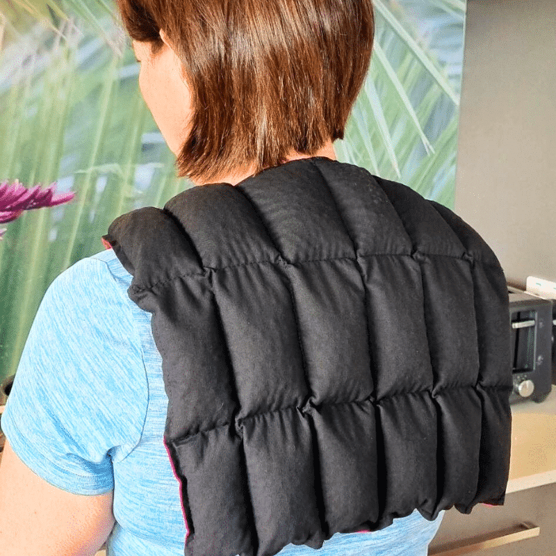 Lady with her back to the camera wearing a black over shoulder wheat bag