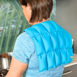 Lady wearing turquosie over shoulder wheat bag while cooking